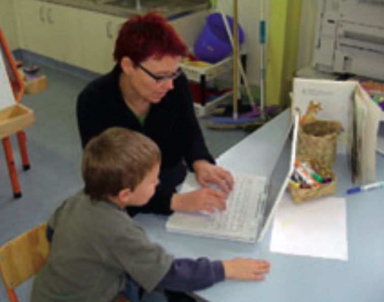 Teacher and child using a laptop computer