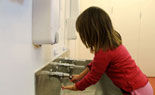 Girl washing her hands in trough sink.