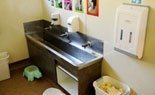 Trough style sink with soap dispensers and hand towels.