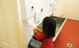 Girl using hand towel dispenser.