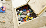 Storage of sand pit toys in wooden storage box.