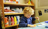 Boy painting with storage shelves in background for art materials.